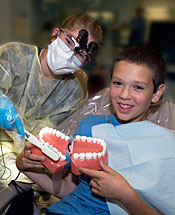 牙科保健师向小男孩展示如何使用牙齿模型和牙刷刷牙。