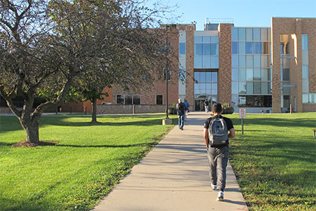 CLC student walking on path to enter the Engineering building