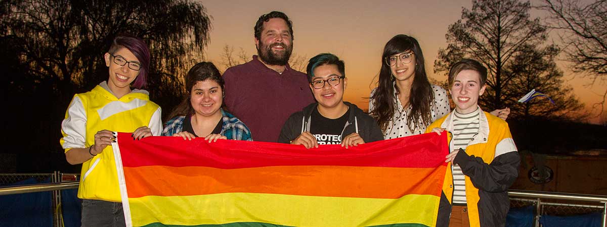 Group of students holding rainbow flag.
