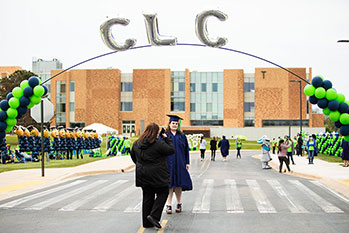 CLC graduate having her photo taken in front of the T building in Grayslake