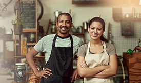 Male and female entrepreneurs wearing aprons in their shop