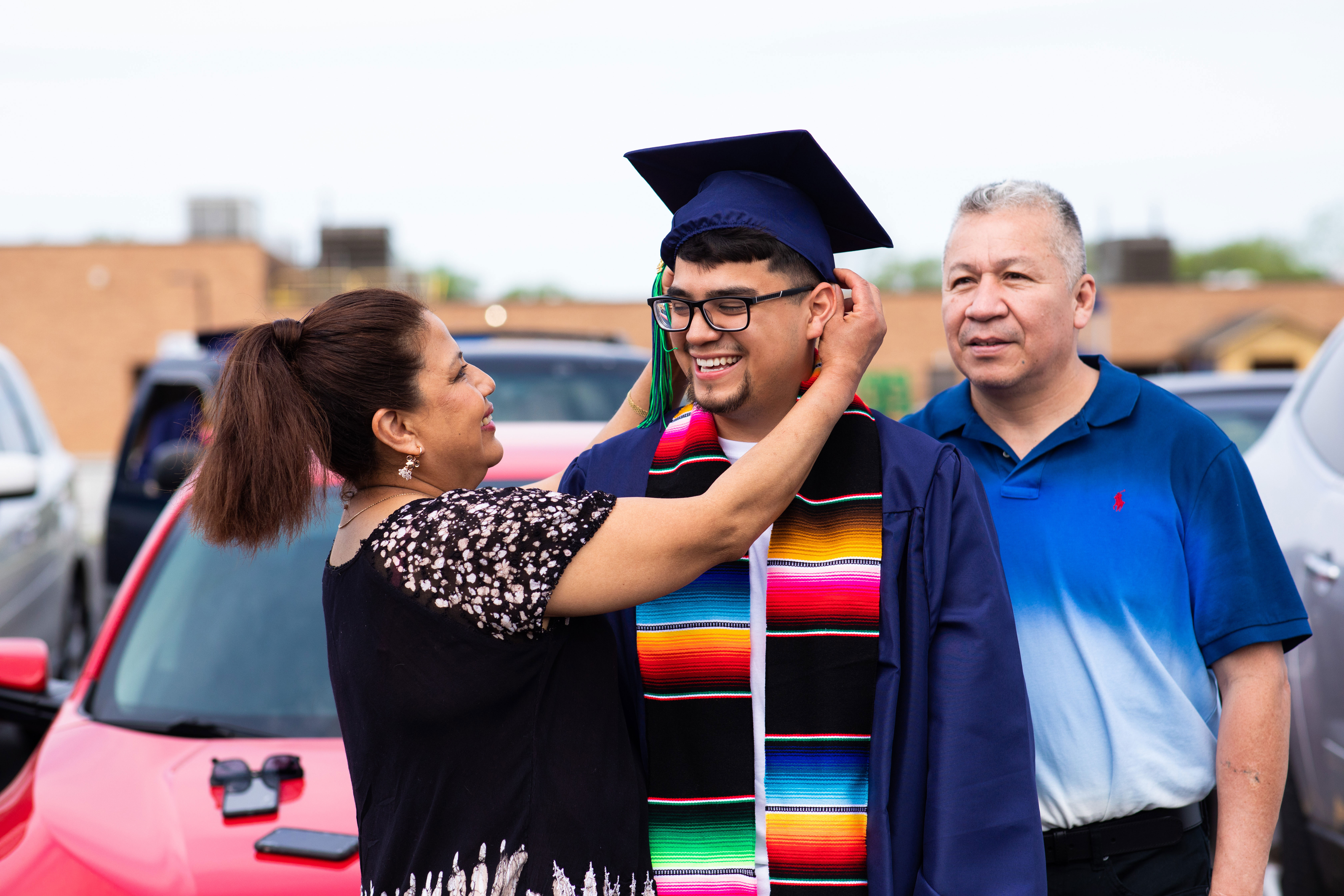 Male Latinx graduate with parents