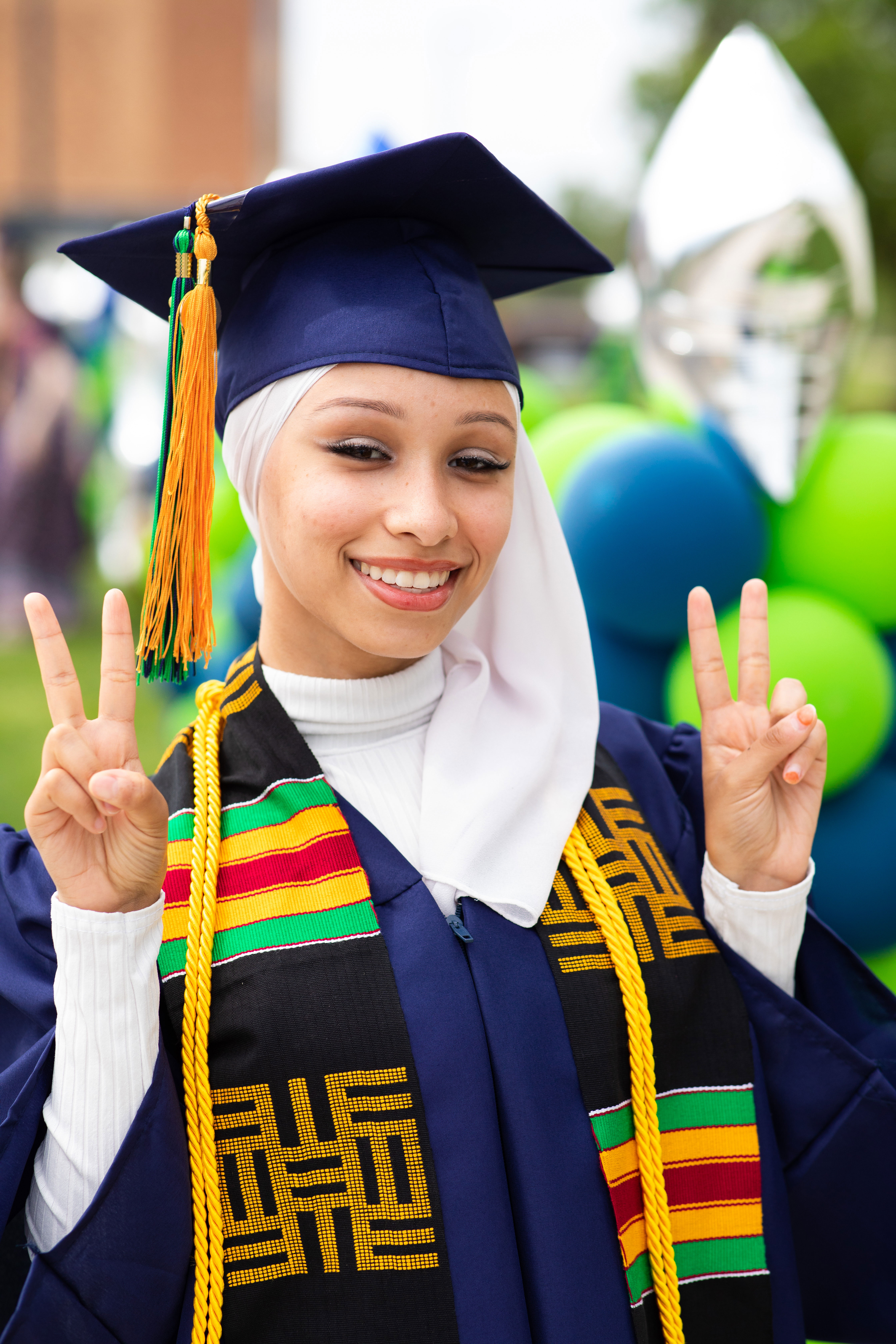 Female graduate holding up peace signs
